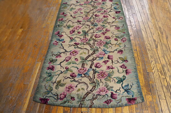 Floral runner in pink, magenta, and teal green lies on distressed wooden plank flooring.