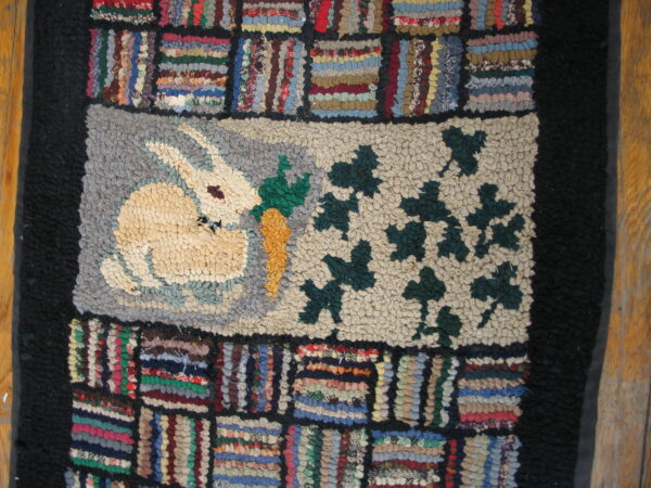 Thick pile rug with a rabbit and vine motif framed by multicolored striped blocks and black borders.