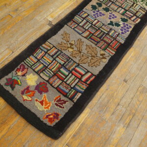Hooked runner rug with alternating multicolored striped blocks and botanical designs, set on distressed wood flooring.