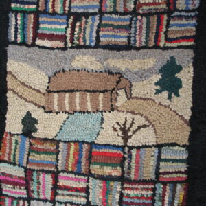 A chunky pile rug featuring a tan house scene bordered by multicolored striped patchwork blocks on wood flooring.