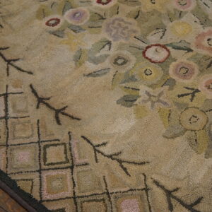 Nubby textured rug detail with floral and geometric designs on a beige ground next to wood flooring.