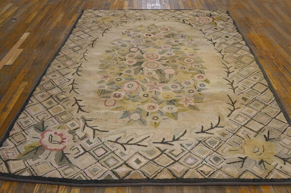Beige rug with a central floral design and diamond trellis border resting on rustic wood floor.