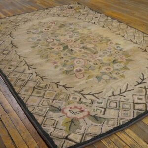Textured floral rug in beige, pink, and green colors featuring a lattice border, laid on rustic wood planks.