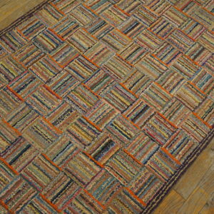 A multicolored textured rag rug runner features a diagonal basketweave pattern on rustic wood floor.