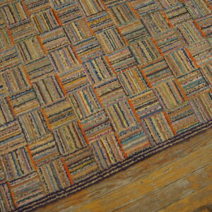 Textured rag rug in faded blues, browns, and oranges, displaying a woven block pattern on wood flooring.