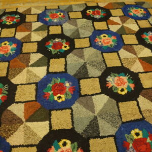 High-pile rug featuring a geometric patchwork of floral blue, black, and earth-toned blocks on wood flooring.