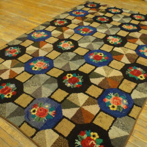 A multicolored hooked rug featuring a geometric pattern of floral octagons and segmented diamond shapes on a wood floor.