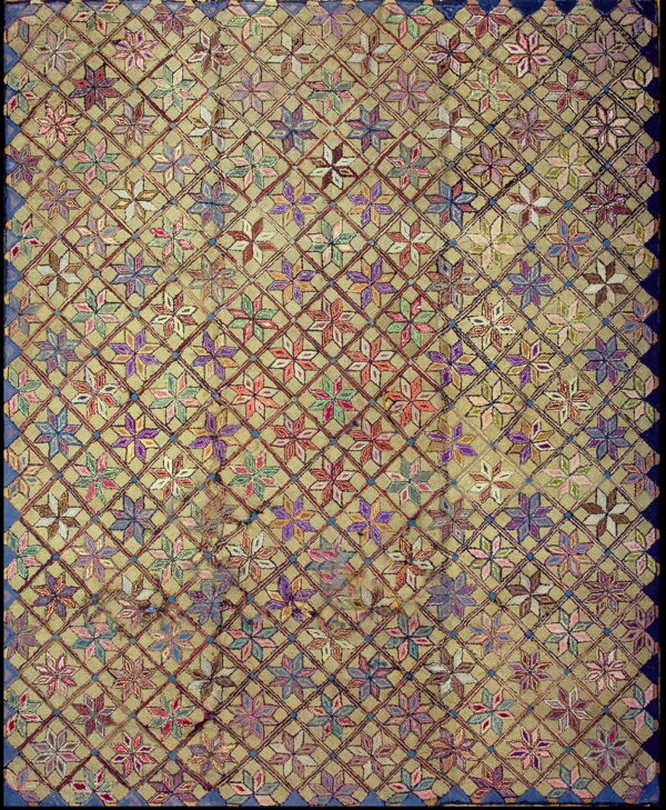 A tan rug field features a dense diamond trellis enclosing vibrant multicolored geometric floral motifs and a dark blue border.