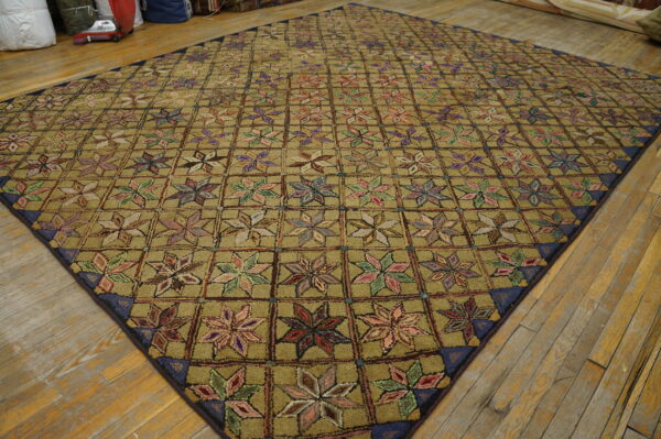 Khaki high-pile rug featuring a repeating grid of colorful, star-like floral motifs rests on wood floors.