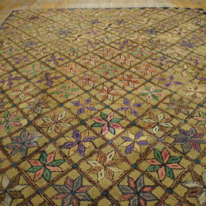 Textured olive rug featuring a multicolor floral pattern inside a dark diamond trellis on wood floor.