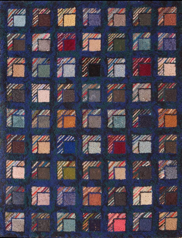 A dark blue hooked rug features a repeating multicolored block pattern resembling log cabin quilt squares.