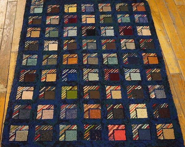 A deep blue rug with a grid of multicolored patchwork squares covers light wood plank flooring.