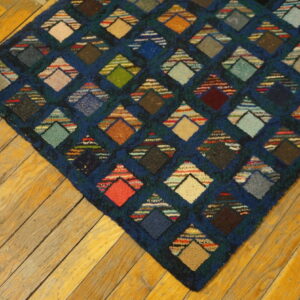 Multi-colored diamond geometric rug with a textured pile on warm-toned diagonal wood flooring.