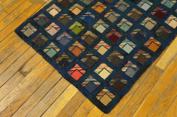 Multi-colored diamond geometric rug with a textured pile on warm-toned diagonal wood flooring.