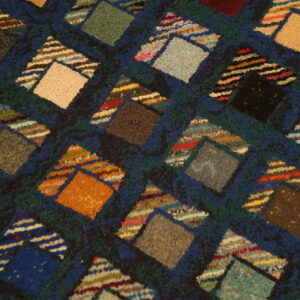 Multicolored geometric rug detail with varied texture showing diamond blocks and striped triangular accents.