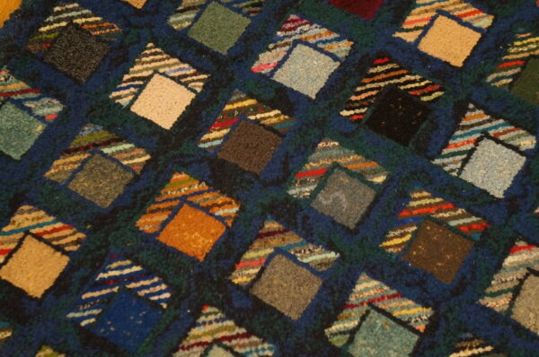 Multicolored geometric rug detail with varied texture showing diamond blocks and striped triangular accents.