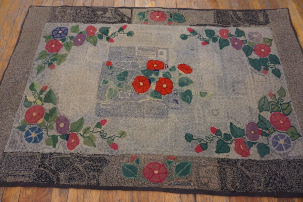 Textured rug featuring red, blue, and purple floral vines and a dark border, set on wood flooring.