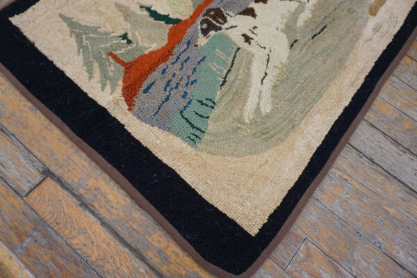 Pictorial hooked rug in cream, slate, and orange with a bold black border lies on distressed wood floors.