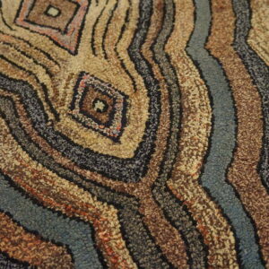 High-texture rug featuring concentric wavy bands and diamond motifs in brown, beige, blue, and black loops.