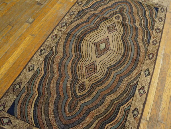 Brown, blue, and tan abstract runner rug with diamond accents placed on distressed wood flooring.