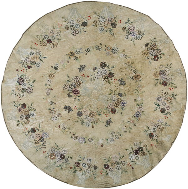 Round beige rug featuring a detailed floral and bird pattern in muted browns, pinks, and blues.