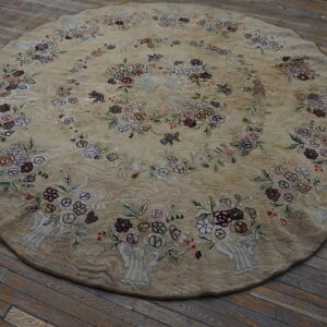 Textured beige round rug with colorful floral bouquets and bird motifs rests on distressed wooden floorboards.