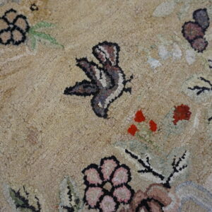 Coarse-textured, high-pile rug with beige field, featuring floral and butterfly motifs in red, pink, and brown.