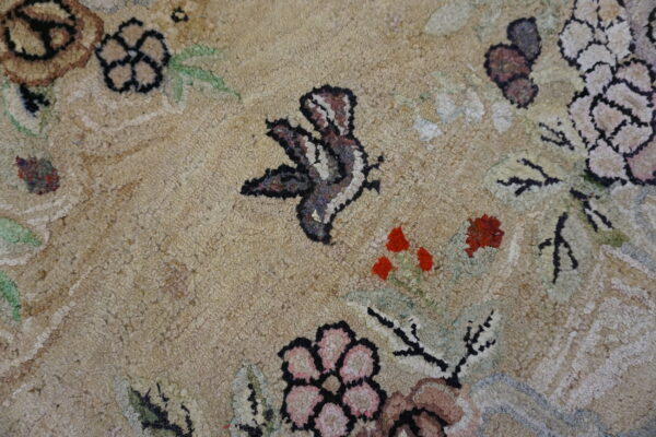Coarse-textured, high-pile rug with beige field, featuring floral and butterfly motifs in red, pink, and brown.