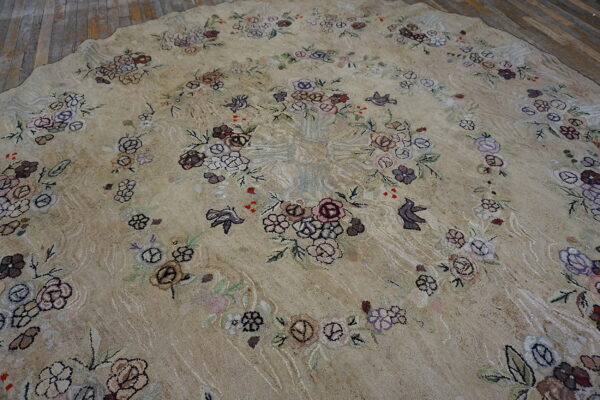 Beige round rug with floral and bird patterns in muted purple, brown, and pink on wood floor.