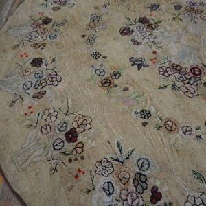 Textured round beige rug with scattered multicolored floral patterns and birds on rustic wood flooring.