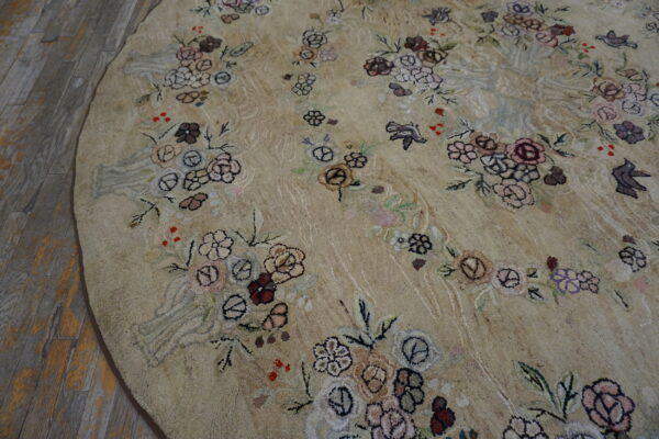 Textured round beige rug with scattered multicolored floral patterns and birds on rustic wood flooring.