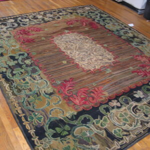 Ornate tapestry-style rug in brown, red, olive, and cream floral patterns lies on light hardwood planks.