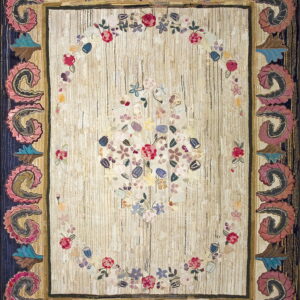 Textured cream rug displaying a colorful floral arrangement and a deep blue border accented by large pink scroll designs.
