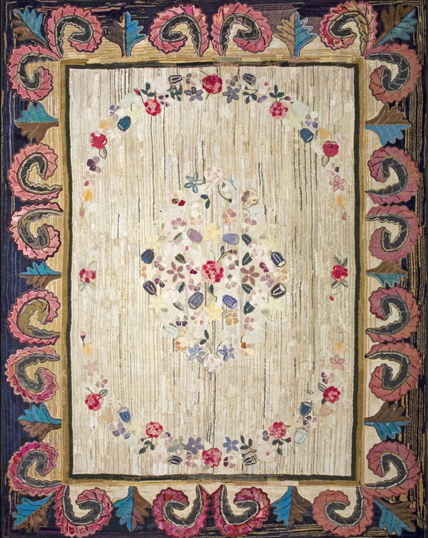 Textured cream rug displaying a colorful floral arrangement and a deep blue border accented by large pink scroll designs.