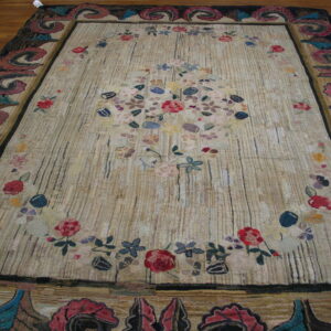 Textured tan rug with vertical lines, a multicolored floral design, and elaborate dark scrolled borders.