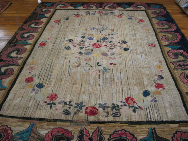 Textured tan rug with vertical lines, a multicolored floral design, and elaborate dark scrolled borders.
