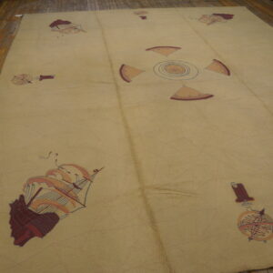 Low-pile tan rug featuring large decorative sailing ship and compass patterns on rustic hardwood floorboards.