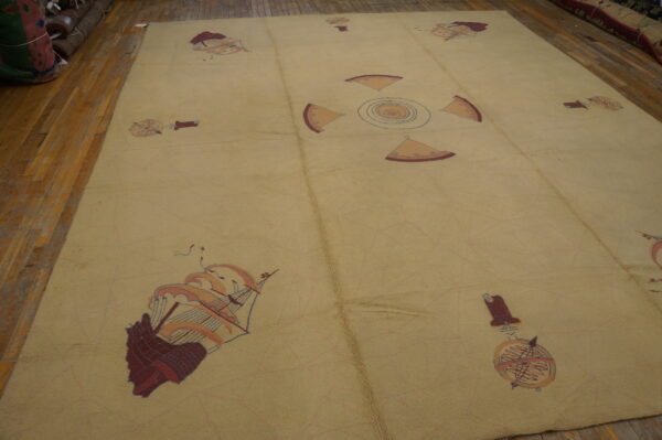 Low-pile tan rug featuring large decorative sailing ship and compass patterns on rustic hardwood floorboards.