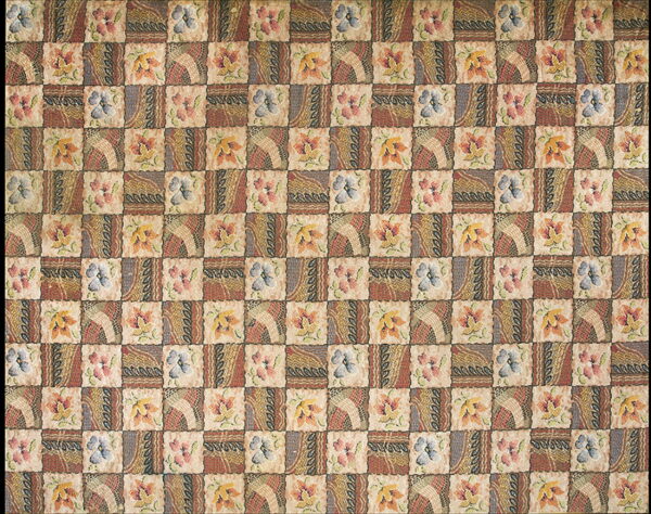 Muted earth tones and blue cover this patchwork rug featuring alternating floral and geometric squares.