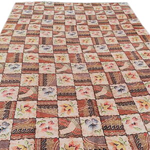 Checkerboard rug with alternating squares of rustic geometric patterns and light floral designs.