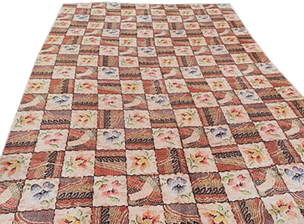 Checkerboard rug with alternating squares of rustic geometric patterns and light floral designs.
