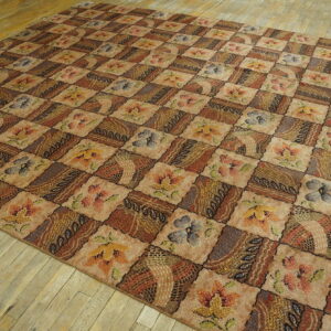 Earthy toned patchwork rug with floral and abstract squares resting on worn light wooden floorboards.