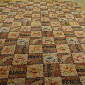 Earth-toned checkered rug featuring floral and abstract blocks lies on a light wooden floor.