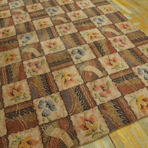Brown and beige patchwork rug with multicolored floral designs laid over distressed wood planks.