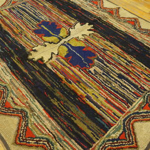 High-texture rug with multicolored stripes and a beige zigzag border resting on light wood floors.