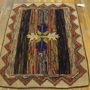 Multicolor textured rug features vertical stripes, a central blue design, and a red zigzag border on wood.