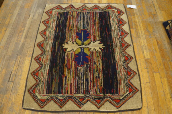 Multicolor textured rug features vertical stripes, a central blue design, and a red zigzag border on wood.