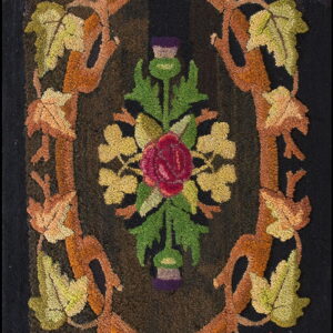 A dark hooked rug features a vine oval border framing a central red rose and colorful autumn leaves.
