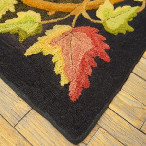 Highly textured rug corner with black background and bright green, yellow, and red autumn leaves on wood flooring.