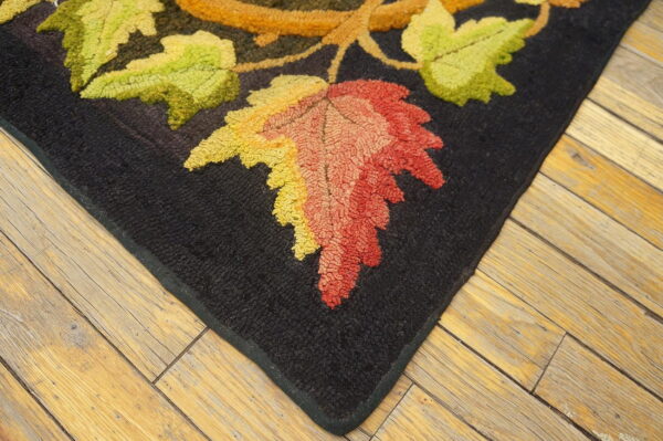 Highly textured rug corner with black background and bright green, yellow, and red autumn leaves on wood flooring.